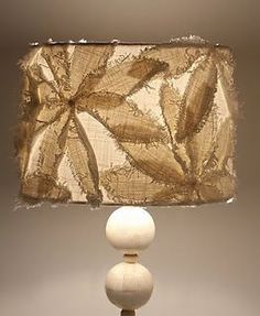 a lamp that is sitting on top of a wooden base with a fabric shade over it