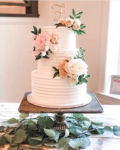 a white wedding cake with pink flowers and greenery