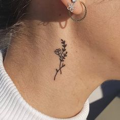 a woman with a flower tattoo on her neck and behind her ear, looking to the side