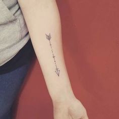 a woman's arm with an arrow tattoo on the left side of her arm