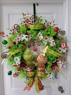 a christmas wreath with two green and red decorations on it, hanging from a door