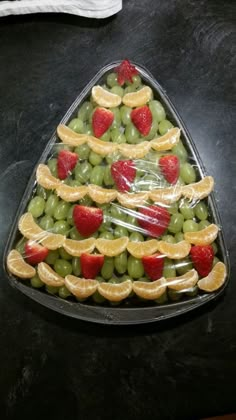 a christmas tree made out of grapes, oranges and strawberries