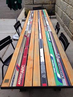 a long wooden table with skis painted on the side and chairs sitting around it