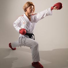 the woman is practicing her karate moves with red boxing gloves on his arm and feet