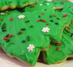 green decorated cookies on a plate with red and white sprinkles in the shape of trees