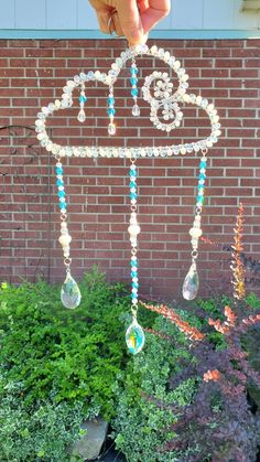 someone is holding up a beaded wind chime in front of a brick wall