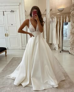 a woman taking a selfie in her wedding dress while looking at her cell phone