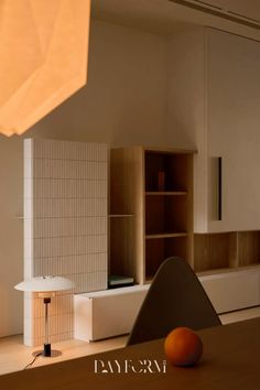 an orange sitting on top of a wooden table next to a white shelf filled with books