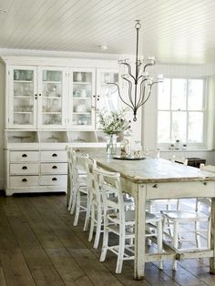 a white dining room table and chairs in front of a china cabinet with glass doors