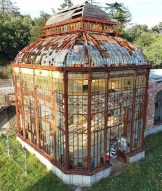 an old glass house in the middle of some grass