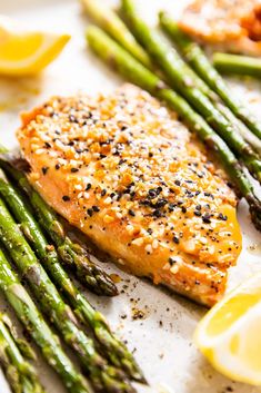 salmon and asparagus on a plate with lemon wedges