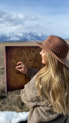 a woman in a hat is looking at a map