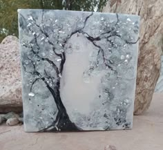 a painting on a rock with trees and rocks in the background