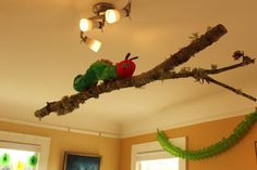 a green caterpillar sitting on top of a tree branch next to a window