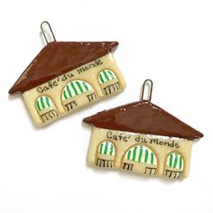 two small ceramic houses with green and white awnings on them, one has a brown roof