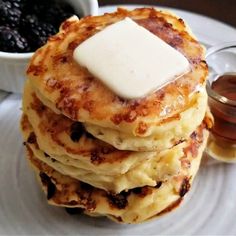 a stack of pancakes with butter on top and syrup in a bowl next to it