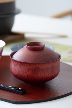 a wooden bowl sitting on top of a table next to a cell phone and pen