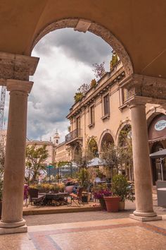 an arch in the middle of a courtyard with tables and chairs