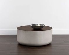 a bowl sitting on top of a wooden table next to a white wall and hardwood floor