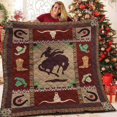 a woman is holding up a quilt that has a horse and rider on it in front of a christmas tree