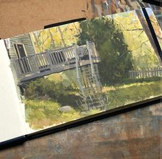 an open book with a painting of a wooden bridge in the middle and trees behind it