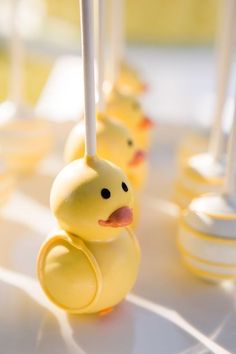 yellow rubber ducks lined up in rows on a table with white candles and candy sticks