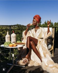 a woman sitting on top of a wooden bench next to a table filled with food