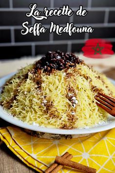 a white plate topped with shredded cheese and raisins next to a yellow napkin