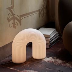 a white object sitting on top of a floor next to a pile of books