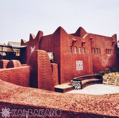 a building made out of red bricks sitting on top of a dirt field