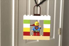 an ornament made out of legos is hanging from a door handle on a string