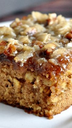 a piece of cake sitting on top of a white plate with nuts and caramel topping