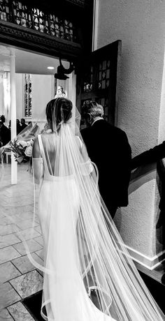 the bride is walking down the aisle with her veil blowing in the wind as she waits for her groom