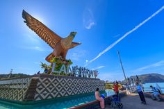 a large bird statue sitting on the side of a body of water