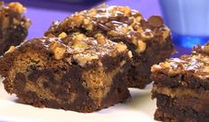 some brownies are on a white plate with chocolate and walnuts in the middle