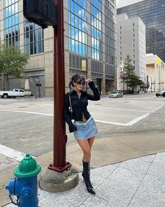 a woman leaning against a pole on the sidewalk