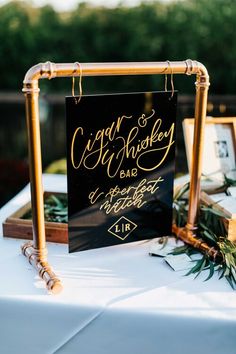 a black and gold sign sitting on top of a white table next to framed pictures