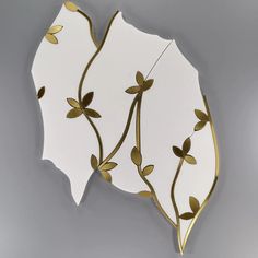 a white and gold leaf shaped mirror hanging on the wall