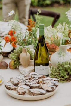 a bottle of wine sitting on top of a table next to plates and vases