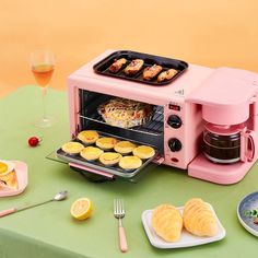 a pink toaster oven sitting on top of a table next to plates of food