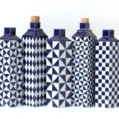 four black and white vases are lined up in a row on a white surface