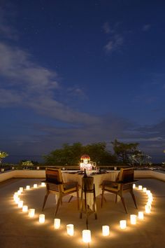 an outdoor dining area with candles lit up on the table and chairs in the middle