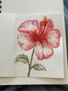 a drawing of a pink flower on top of a piece of paper next to a pair of jeans