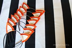 an orange and white striped table cloth with some scissors on top of the black and white stripes