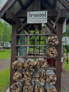 there are many logs stacked up on the rack in front of the shed and sign