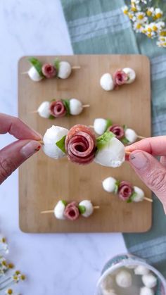 a person is holding up some food on a stick with marshmallows and other toppings