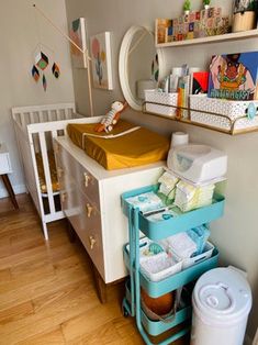 a baby's room with a crib, changing table and shelves on the wall