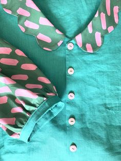 a green shirt with pink polka dots and buttons on the collar is seen from above