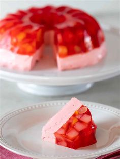 a strawberry jello cake on a white plate with a slice cut out and ready to be eaten