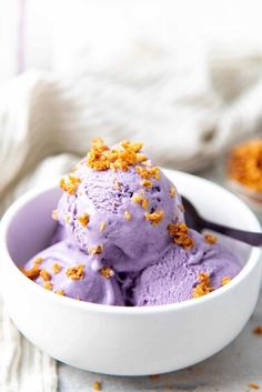 a white bowl filled with purple ice cream and sprinkled orange crumbs